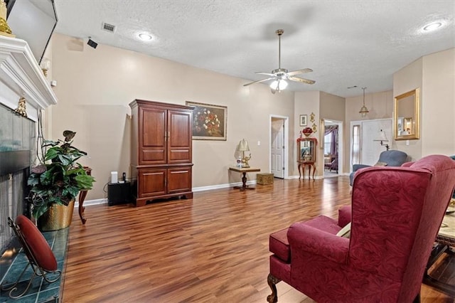 living room featuring ceiling fan, hardwood / wood-style floors, and a textured ceiling