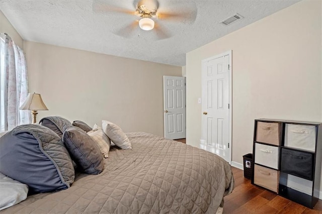 bedroom with ceiling fan, dark hardwood / wood-style flooring, and a textured ceiling