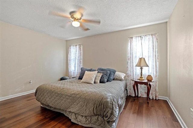 bedroom with a textured ceiling, ceiling fan, and dark wood-type flooring