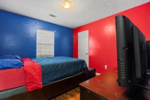 bedroom featuring hardwood / wood-style flooring and a textured ceiling