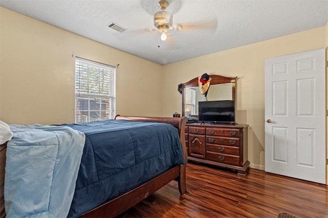 bedroom with ceiling fan, dark hardwood / wood-style flooring, and a textured ceiling