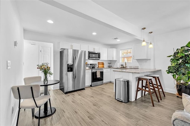 2912 Palm Dr, East Point, GA 30344 - kitchen with appliances with stainless steel finishes, a peninsula, baseboards, light wood-type flooring, and white cabinetry