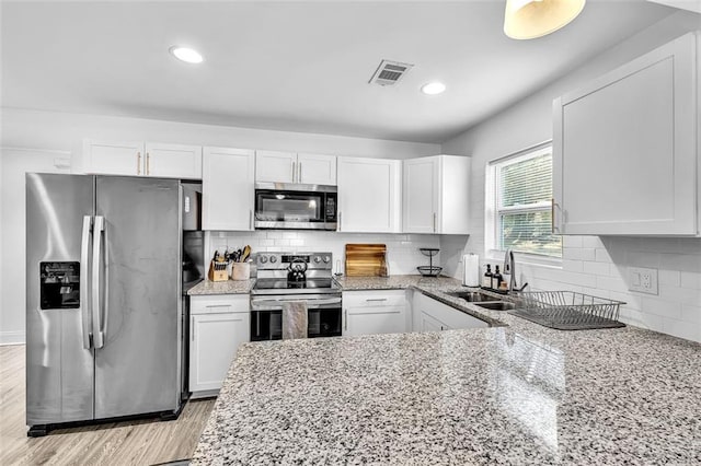 2912 Palm Dr, East Point, GA 30344 - kitchen featuring appliances with stainless steel finishes, a sink, white cabinets, light stone countertops, and tasteful backsplash