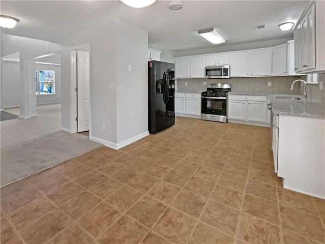 kitchen with white cabinets, sink, decorative backsplash, light stone countertops, and appliances with stainless steel finishes