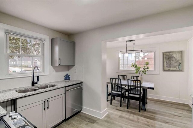 kitchen featuring hanging light fixtures, light hardwood / wood-style floors, gray cabinetry, dishwasher, and sink