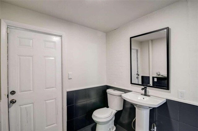 bathroom with tile walls and toilet