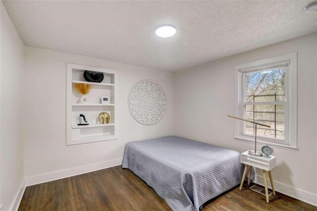 bedroom featuring a textured ceiling and dark hardwood / wood-style flooring