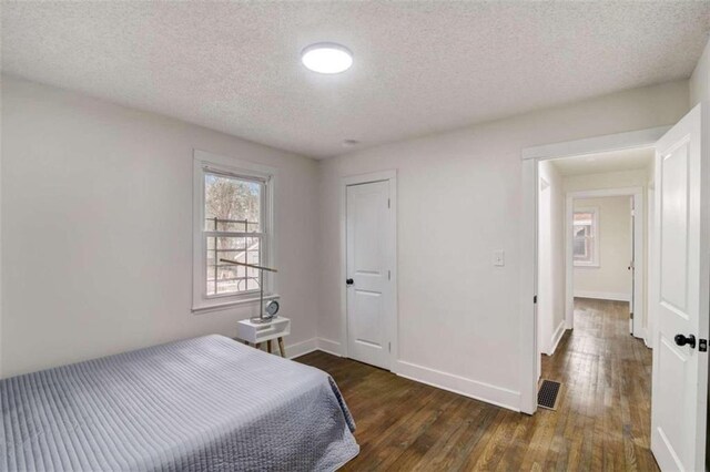 bedroom featuring a textured ceiling and dark hardwood / wood-style floors