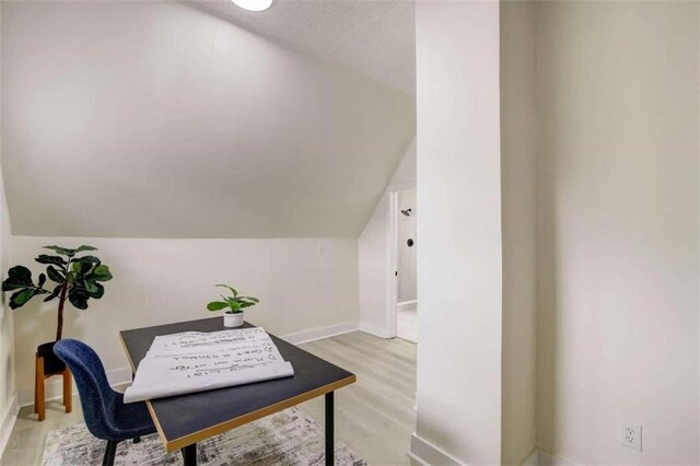 office with light wood-type flooring and vaulted ceiling