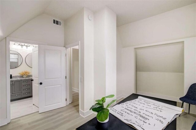 bathroom featuring wood-type flooring, lofted ceiling, and vanity