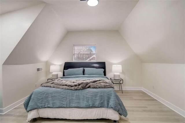 bedroom featuring light wood-type flooring and vaulted ceiling