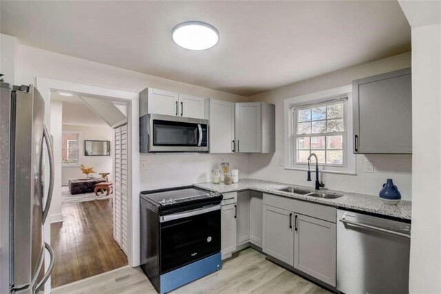 kitchen featuring appliances with stainless steel finishes, gray cabinetry, light wood-type flooring, and sink