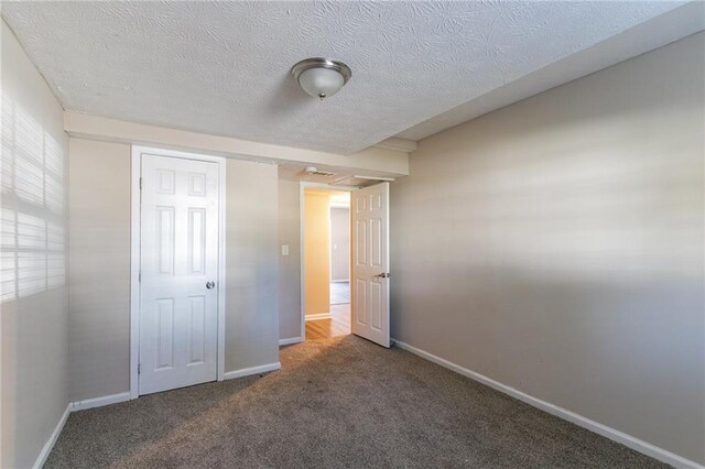 unfurnished bedroom with dark carpet and a textured ceiling