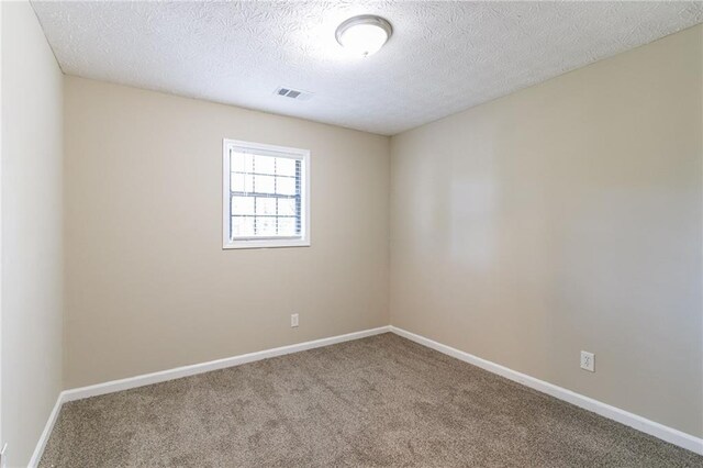 carpeted empty room featuring a textured ceiling