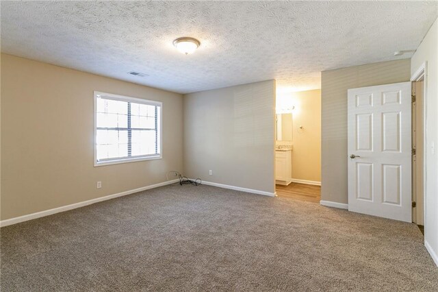 spare room featuring carpet and a textured ceiling