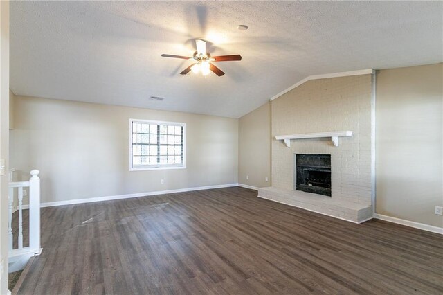 unfurnished living room with a brick fireplace, a textured ceiling, ceiling fan, dark wood-type flooring, and lofted ceiling