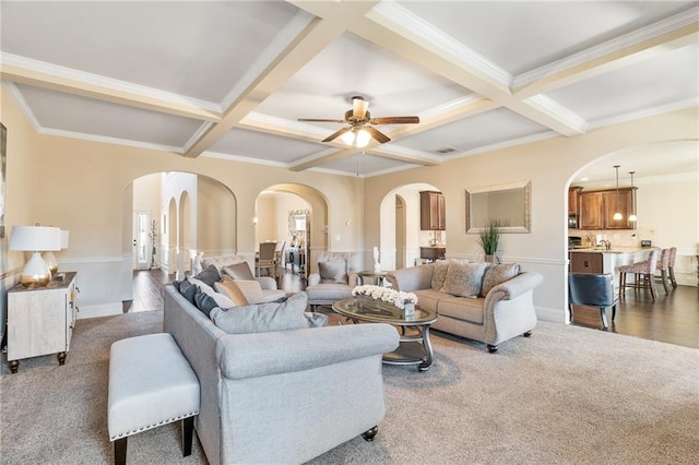 living area featuring coffered ceiling, arched walkways, and carpet