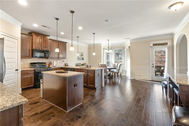 kitchen featuring dark wood finished floors, a kitchen island, black appliances, a peninsula, and crown molding