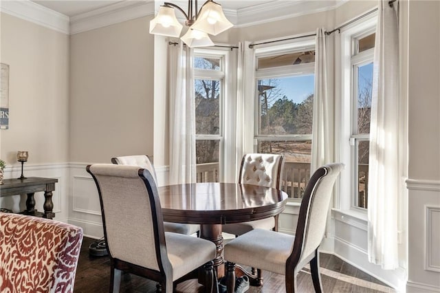 dining space with wood finished floors, a decorative wall, a wainscoted wall, and ornamental molding