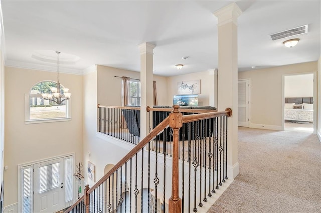 corridor featuring an upstairs landing, visible vents, a chandelier, and decorative columns