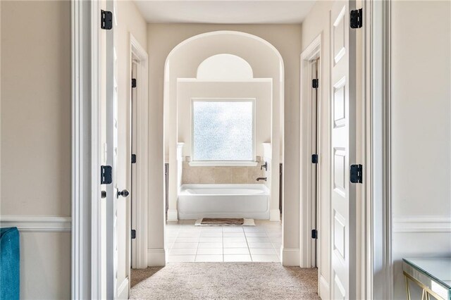 hallway featuring tile patterned floors, carpet floors, and baseboards