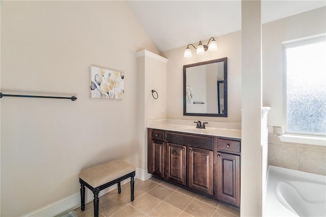 bathroom featuring a healthy amount of sunlight, vanity, tile patterned flooring, and vaulted ceiling