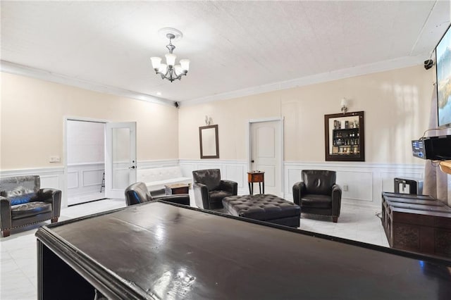 rec room with crown molding, a wainscoted wall, a notable chandelier, and a decorative wall