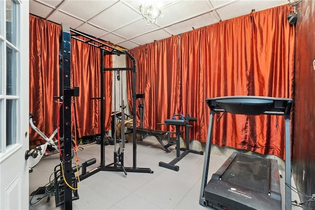workout area with wood walls and a drop ceiling