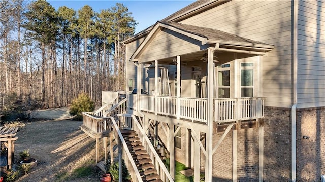 view of home's exterior with a deck, brick siding, ceiling fan, and stairs