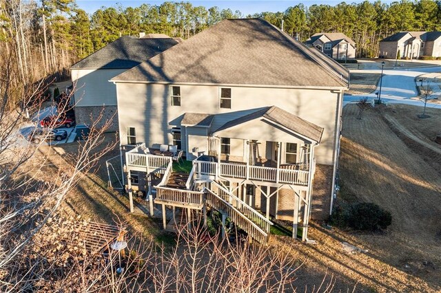 back of house with roof with shingles, stairs, and a wooden deck