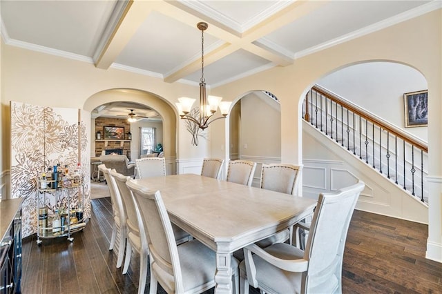 dining area with arched walkways, a fireplace, beamed ceiling, and dark wood-type flooring