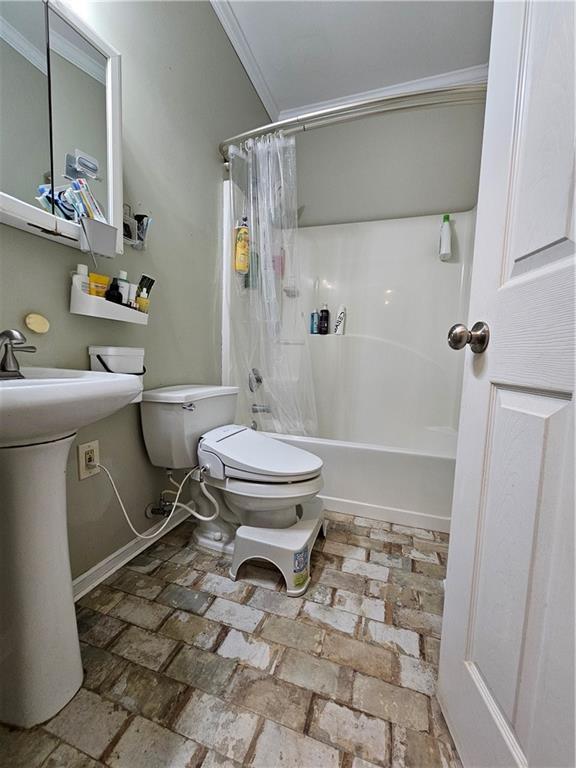1988 Greensferry Gln, Lawrenceville, GA 30043 - full bath featuring toilet, crown molding, shower / bath combo with shower curtain, brick floors, and baseboards