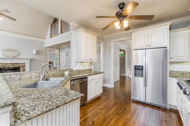 kitchen featuring stainless steel appliances, a ceiling fan, a sink, a fireplace, and dark wood-type flooring
