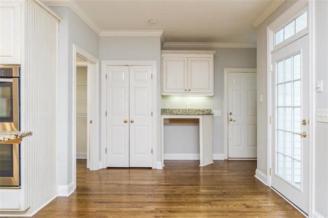 foyer with wood finished floors, crown molding, healthy amount of natural light, and baseboards