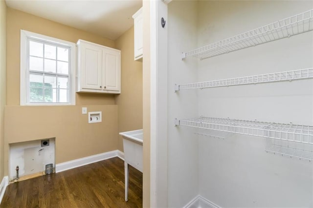 washroom with electric dryer hookup, cabinet space, washer hookup, dark wood-style flooring, and baseboards
