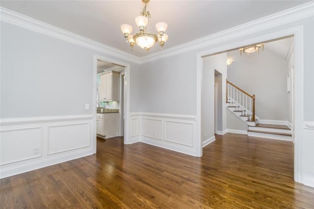 unfurnished dining area featuring a chandelier, stairs, dark wood-style flooring, a wainscoted wall, and crown molding