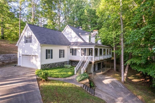 view of front of home featuring driveway, a garage, a chimney, stairway, and roof with shingles
