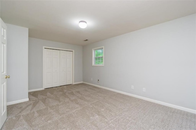 unfurnished bedroom with light colored carpet, baseboards, and a closet