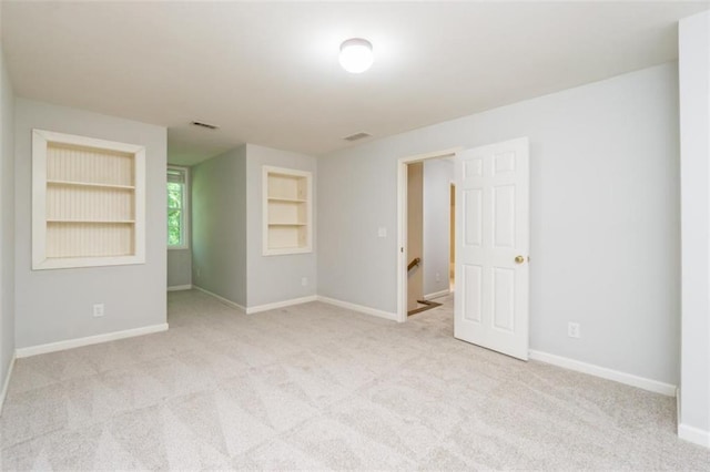 carpeted empty room with built in shelves and baseboards