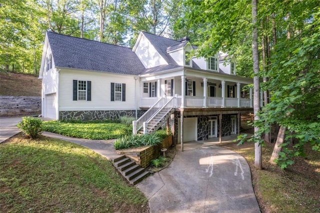 view of front of home featuring a porch, driveway, stairway, an attached garage, and roof with shingles