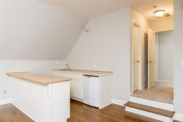 bar area with dark wood-style floors, white dishwasher, baseboards, and lofted ceiling