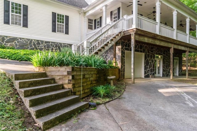 view of side of home featuring a ceiling fan, stairway, asphalt driveway, and a garage