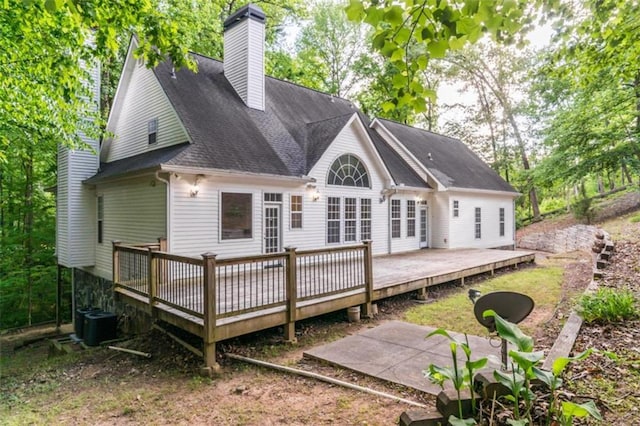 back of house featuring a chimney, roof with shingles, a deck, and central AC