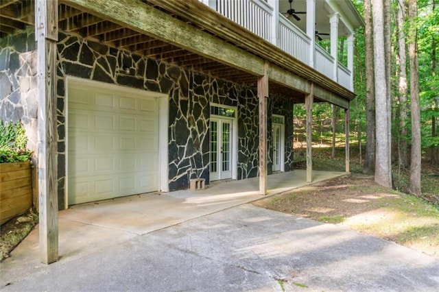 entrance to property featuring concrete driveway, a ceiling fan, a garage, and french doors