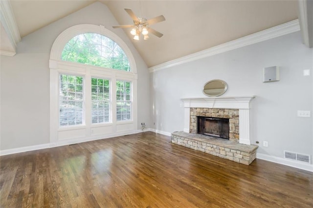 unfurnished living room with a ceiling fan, high vaulted ceiling, a stone fireplace, wood finished floors, and baseboards