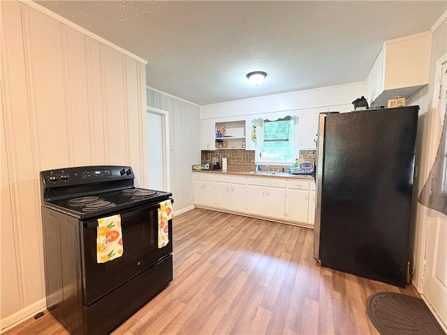 5167 Hiram Lithia Springs Rd, Powder Springs, GA 30127 - kitchen with black electric range oven, freestanding refrigerator, crown molding, light wood-style flooring, and white cabinets