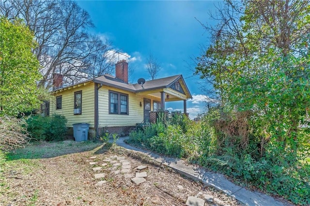 view of home's exterior with a porch and a chimney