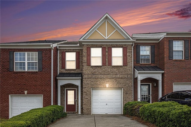 townhome / multi-family property with brick siding, a garage, and concrete driveway