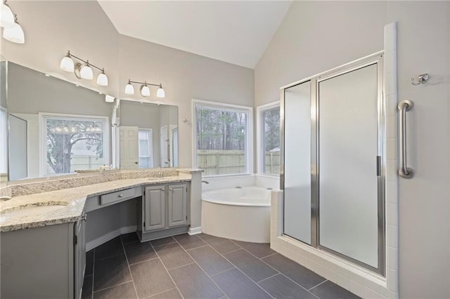 bathroom featuring a stall shower, a garden tub, vaulted ceiling, and vanity