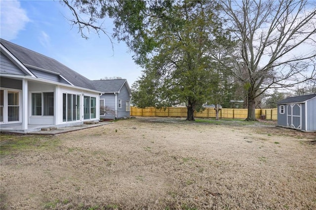 view of yard featuring a sunroom, a shed, fence, and an outbuilding